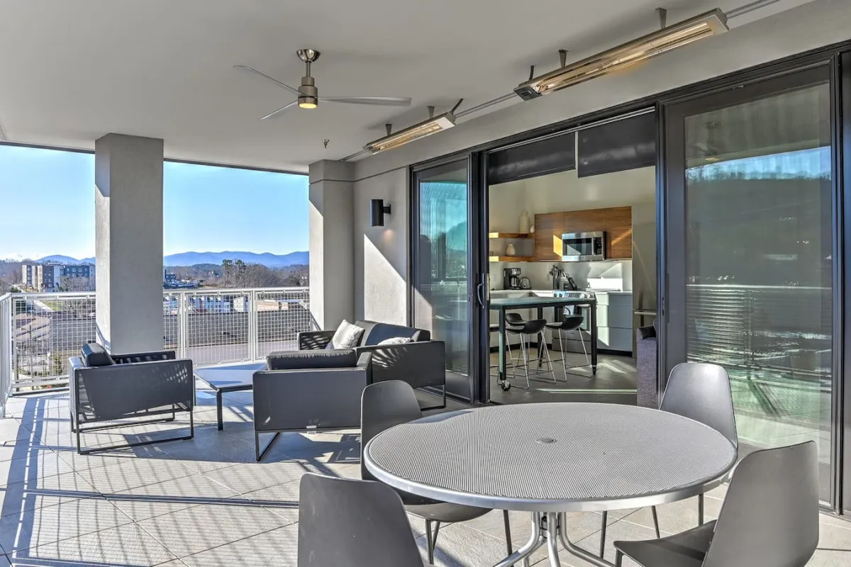 A modern outdoor dining area with views of the mountains and the city, perfect for hosting friends or enjoying a sunset meal. The scene blends urban excitement with a backdrop of natural beauty, inviting residents to partake in Asheville’s unique lifestyle right at their doorstep.