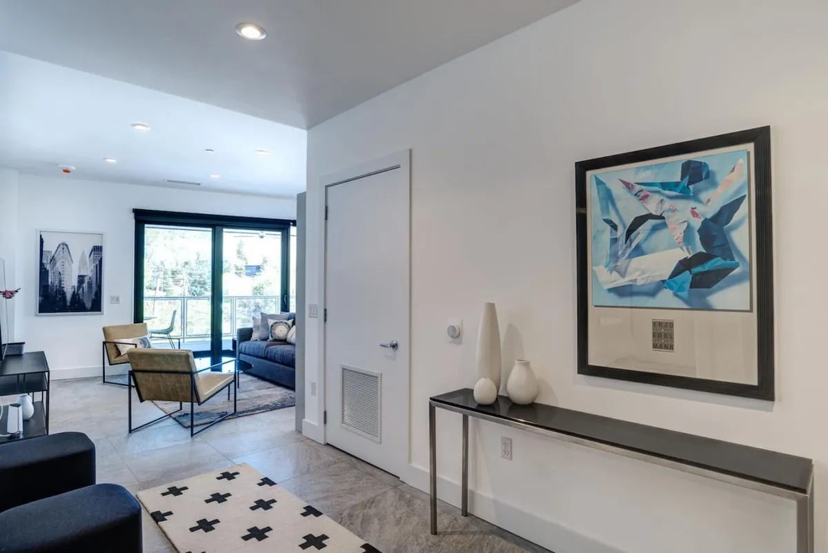 A spacious, modern living area featuring abstract artwork, stylish furniture, and large windows that bathe the room in natural light. The arrangement invites relaxation and socializing, with ample floor space for both humans and their furry companions. The calming atmosphere is enhanced by soft lighting and contemporary decor.
